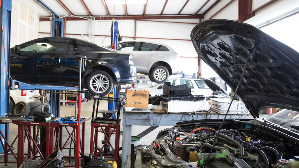 Auto repair shop with cars on lifts and open hood revealing engine bay