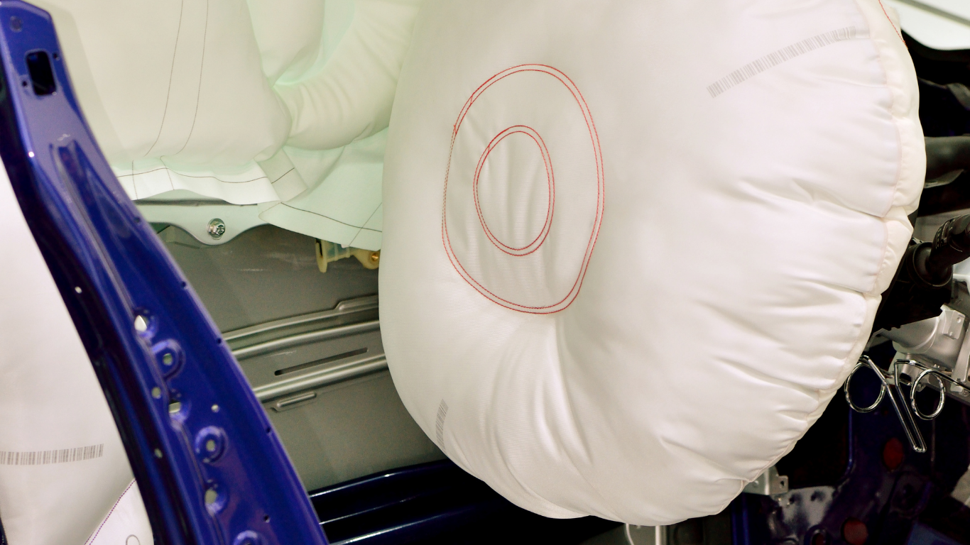 White car seat airbag deployed inside a vehicle, with blue door frame visible