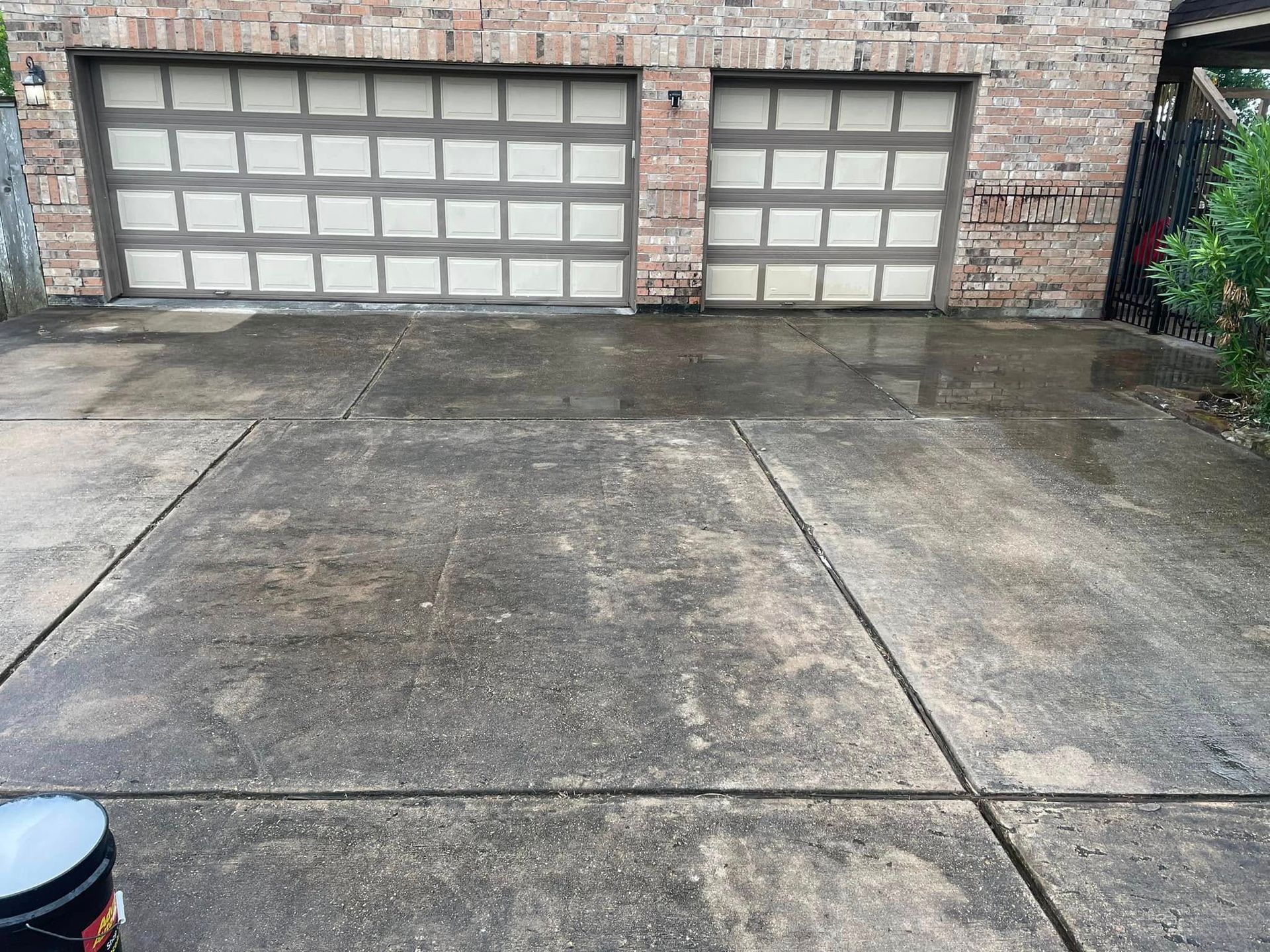 A bucket is sitting on the ground in front of a garage door.