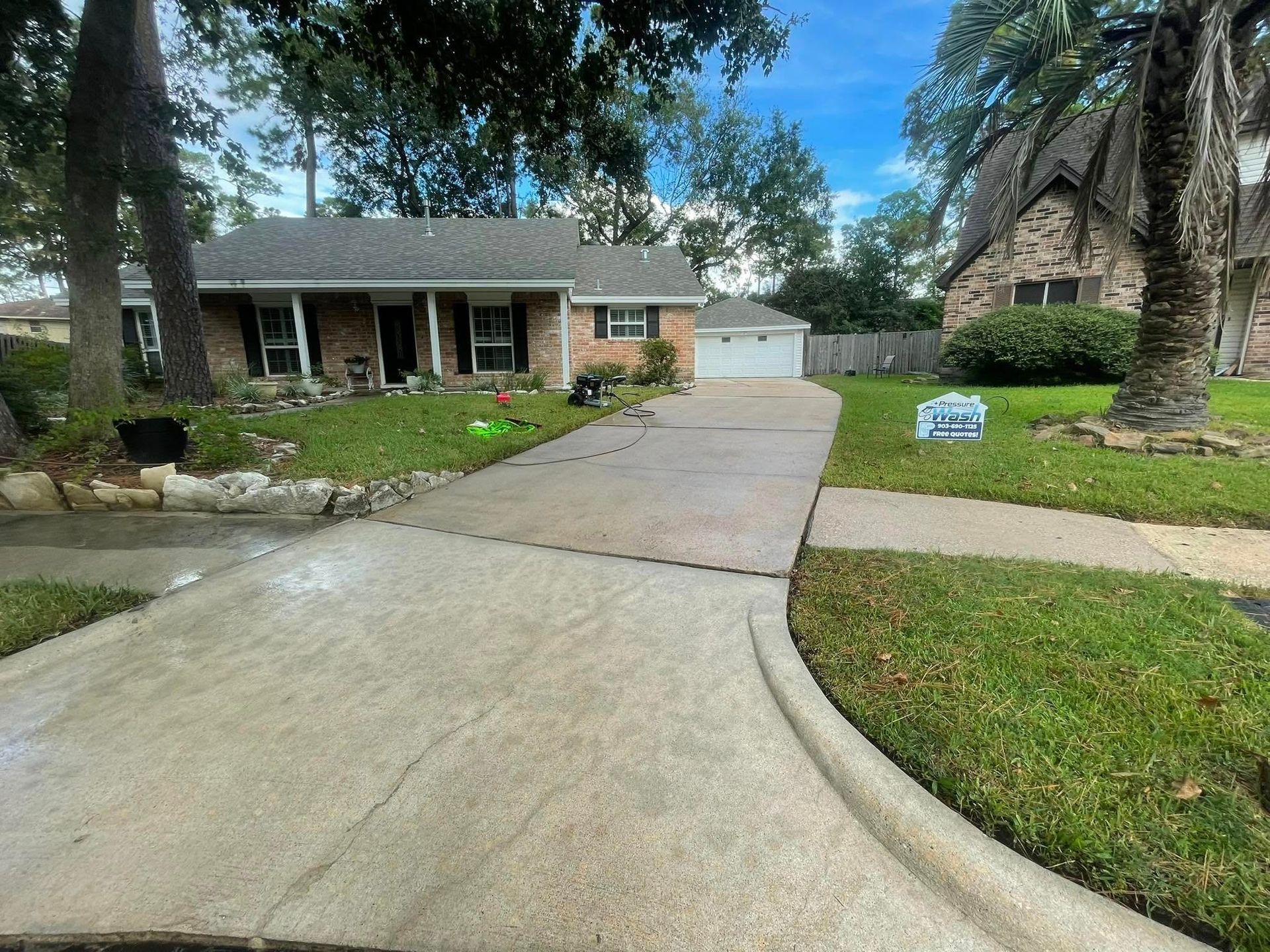 A brick house with a driveway and a palm tree in front of it.