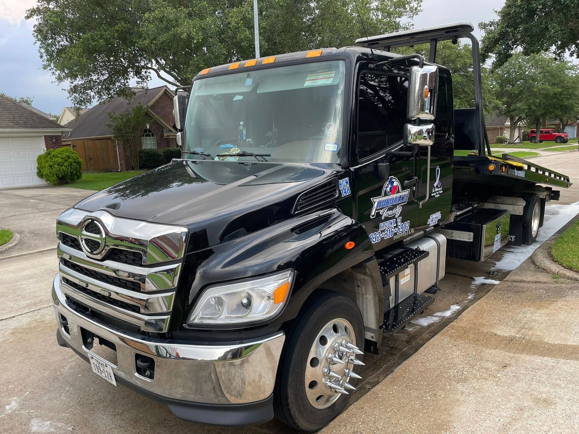 A black tow truck is parked in the driveway of a house.
