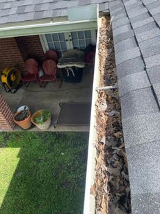 A gutter filled with leaves is sitting on top of a roof.