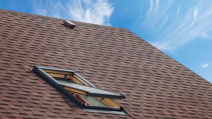 A roof with a skylight on it and a blue sky in the background.