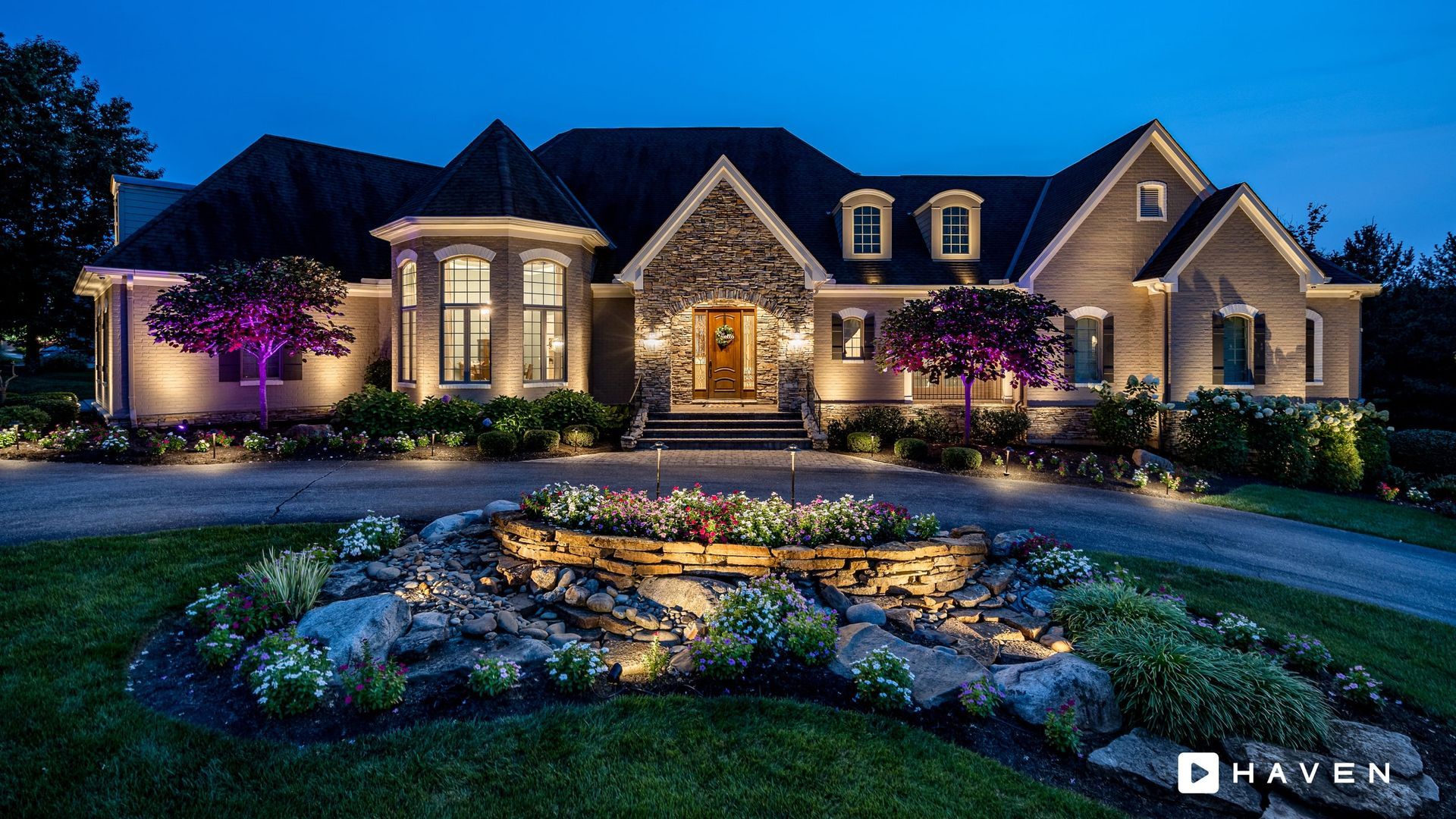 A large house is lit up at night with purple lights