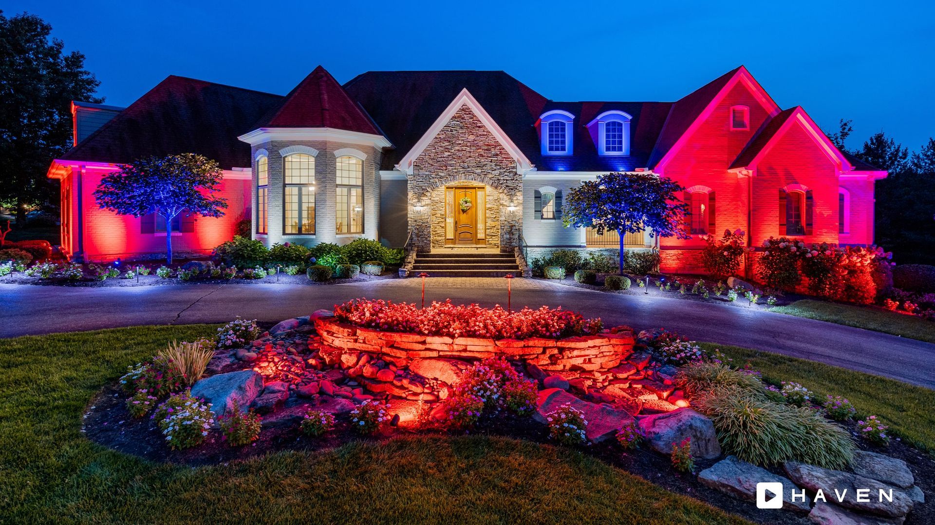 A large house is lit up with red and blue lights at night.