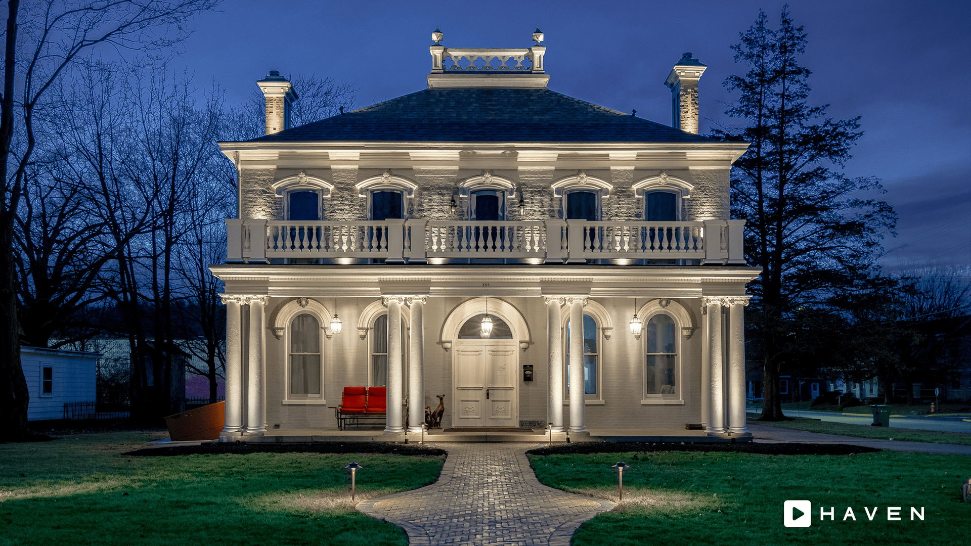 A large white house with columns is lit up at night