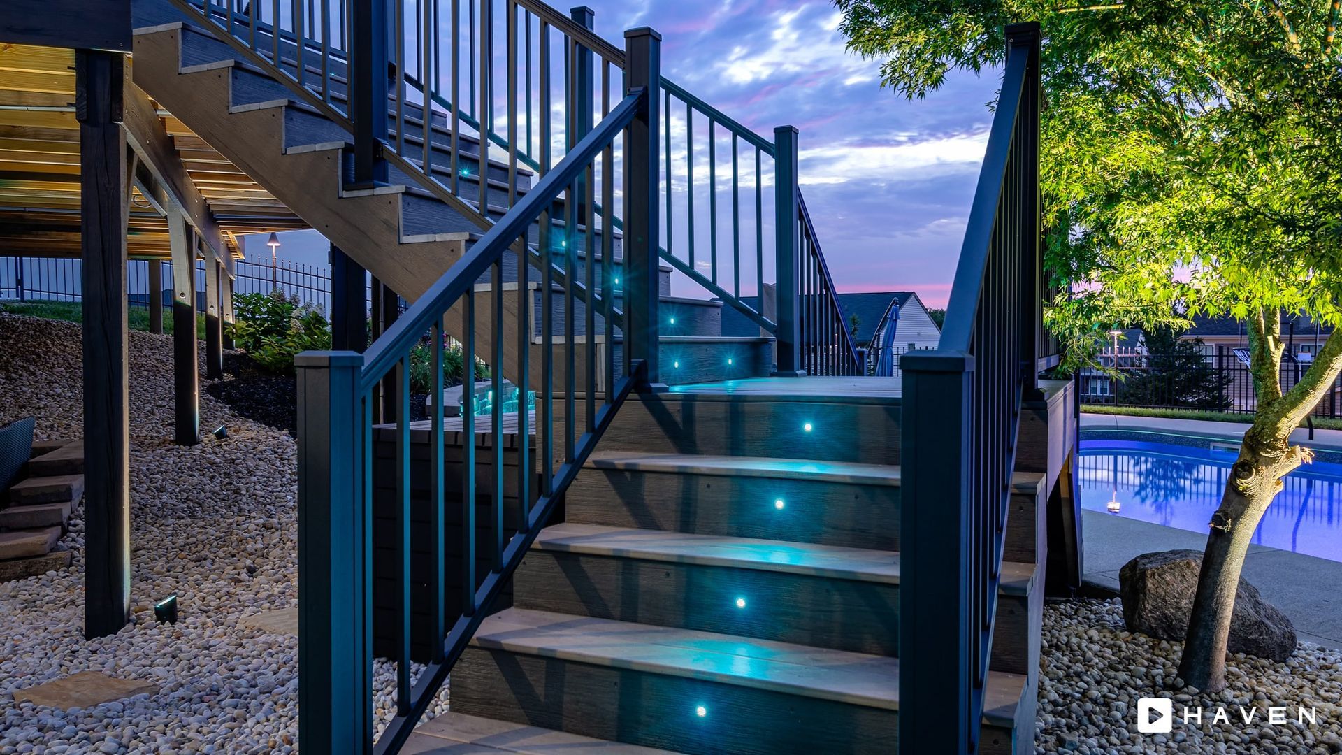 A staircase with lights on the steps and a pool in the background.