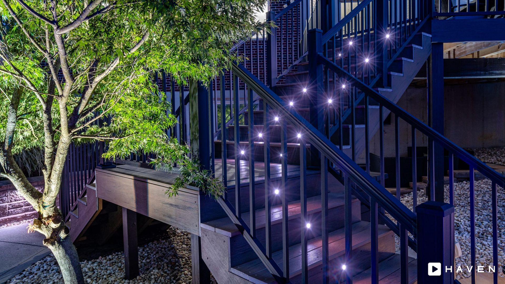 A set of stairs with lights on them and a tree in the background.