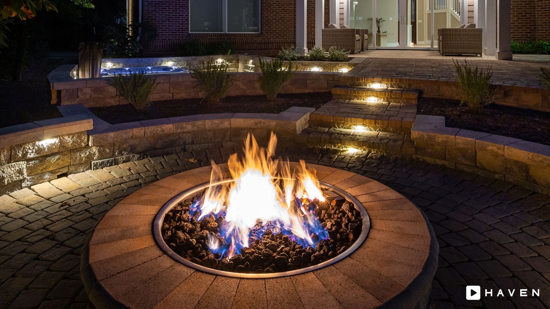 A fire pit is lit up at night in front of a house.
