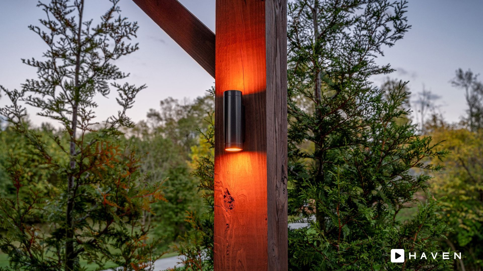 A wooden post with a light on it in the middle of a forest.
