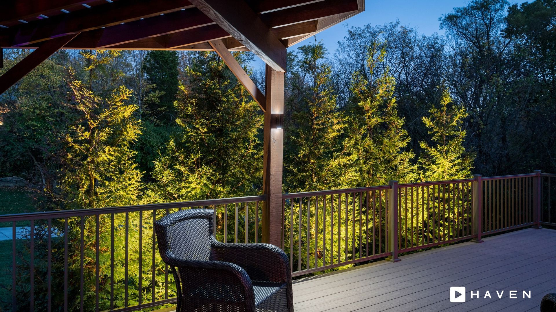 A deck with a chair and trees in the background