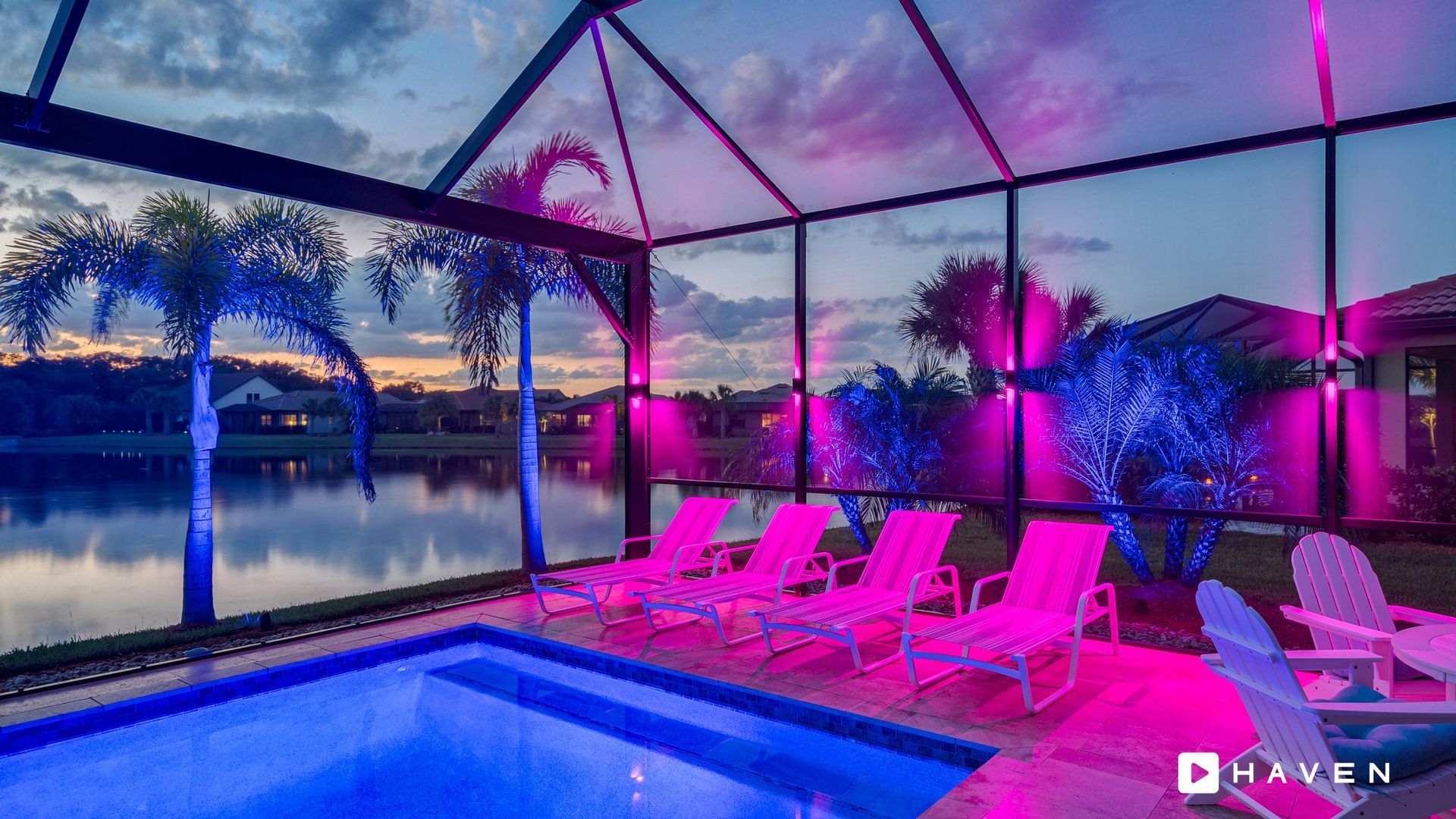 A swimming pool with chairs and a view of a lake at night.