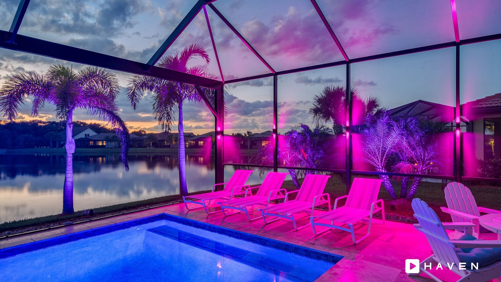 A swimming pool is lit up with pink lights at night.