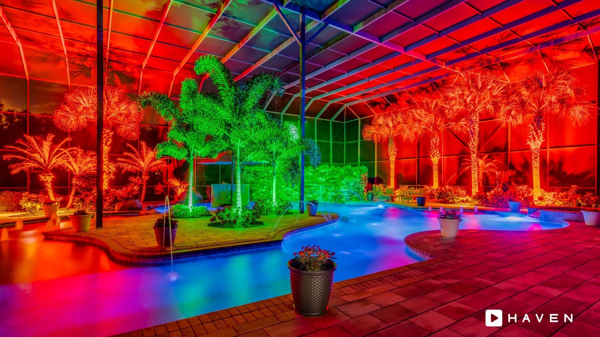 A swimming pool surrounded by trees and lights at night.