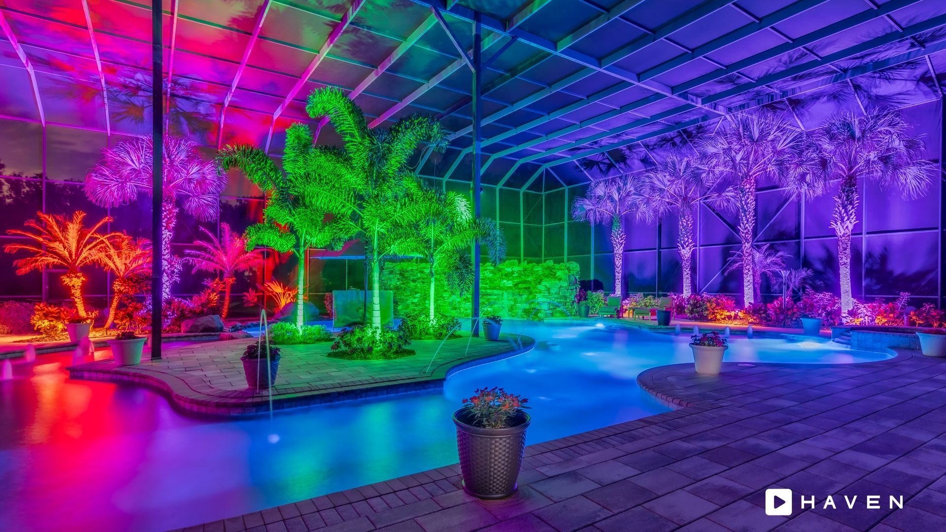A large swimming pool surrounded by trees and lights at night.