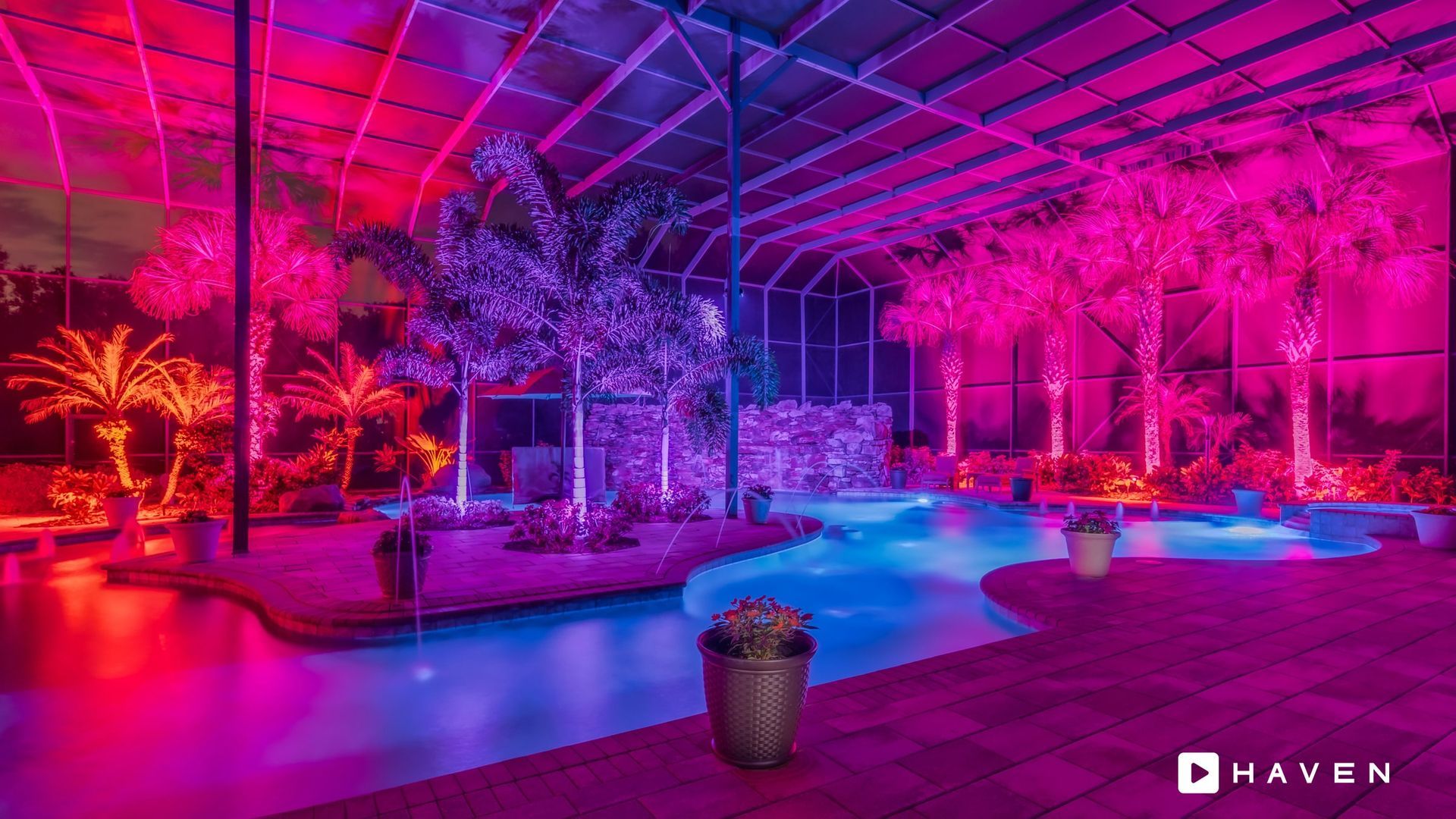 A swimming pool is lit up with purple and blue lights at night.