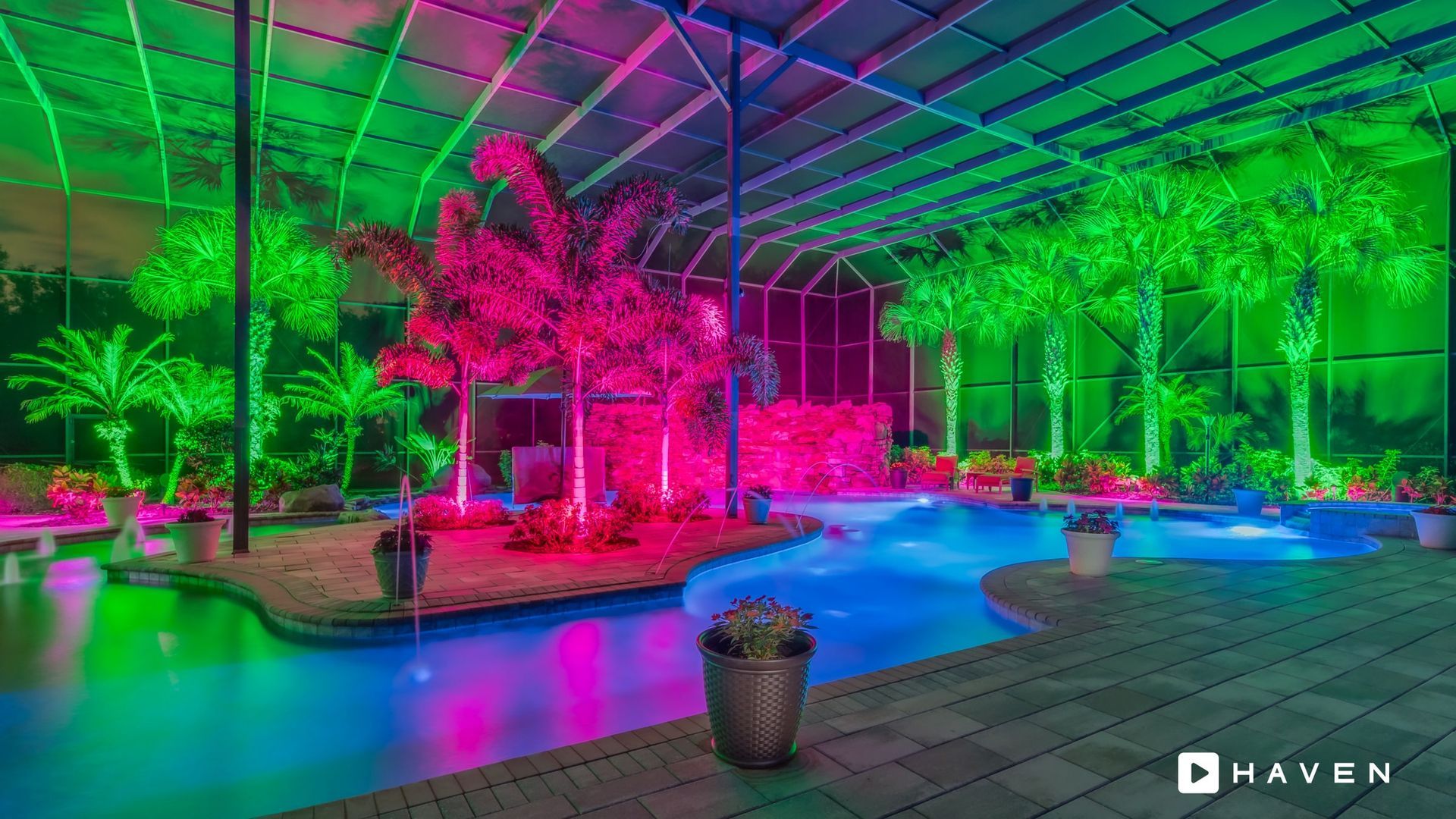 A swimming pool surrounded by trees and lights at night.