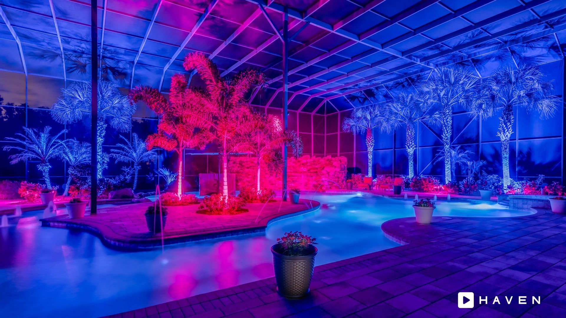 A swimming pool is lit up with purple and blue lights.