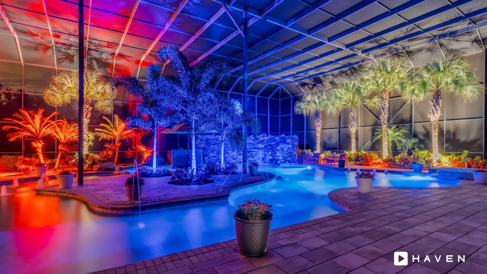 A large swimming pool surrounded by trees and lights at night.