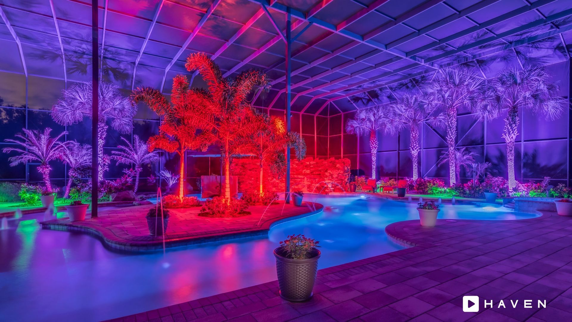 A swimming pool is lit up with purple and red lights.