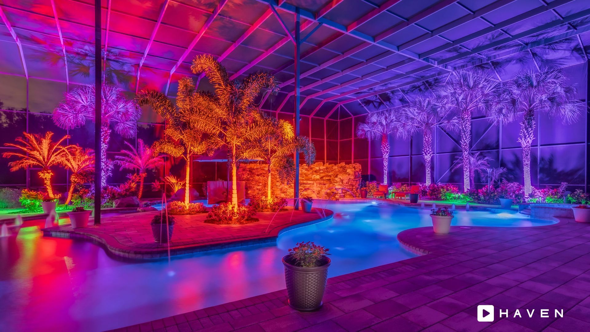 A swimming pool surrounded by trees and lights at night.