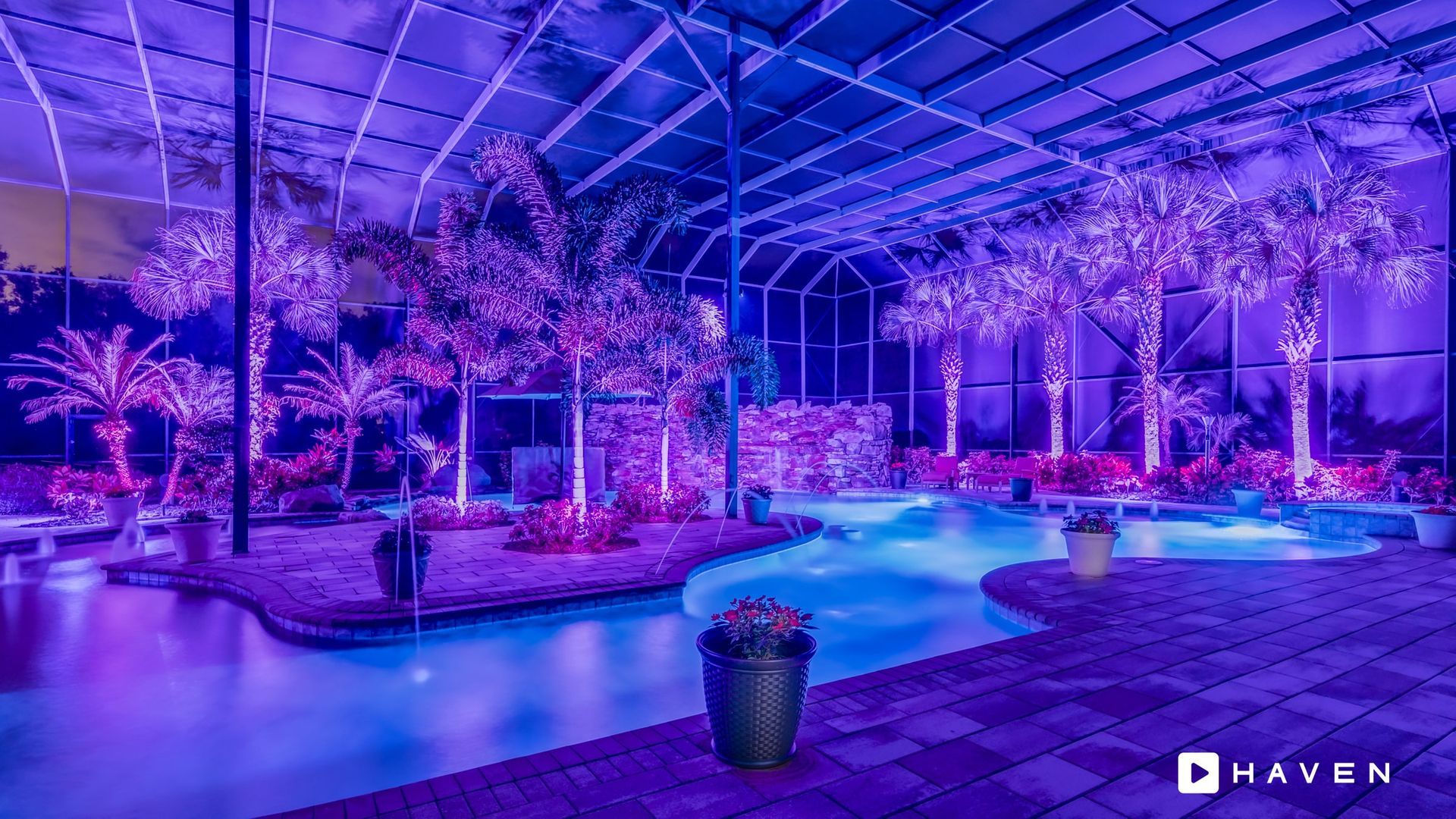 A swimming pool is lit up with purple lights at night.