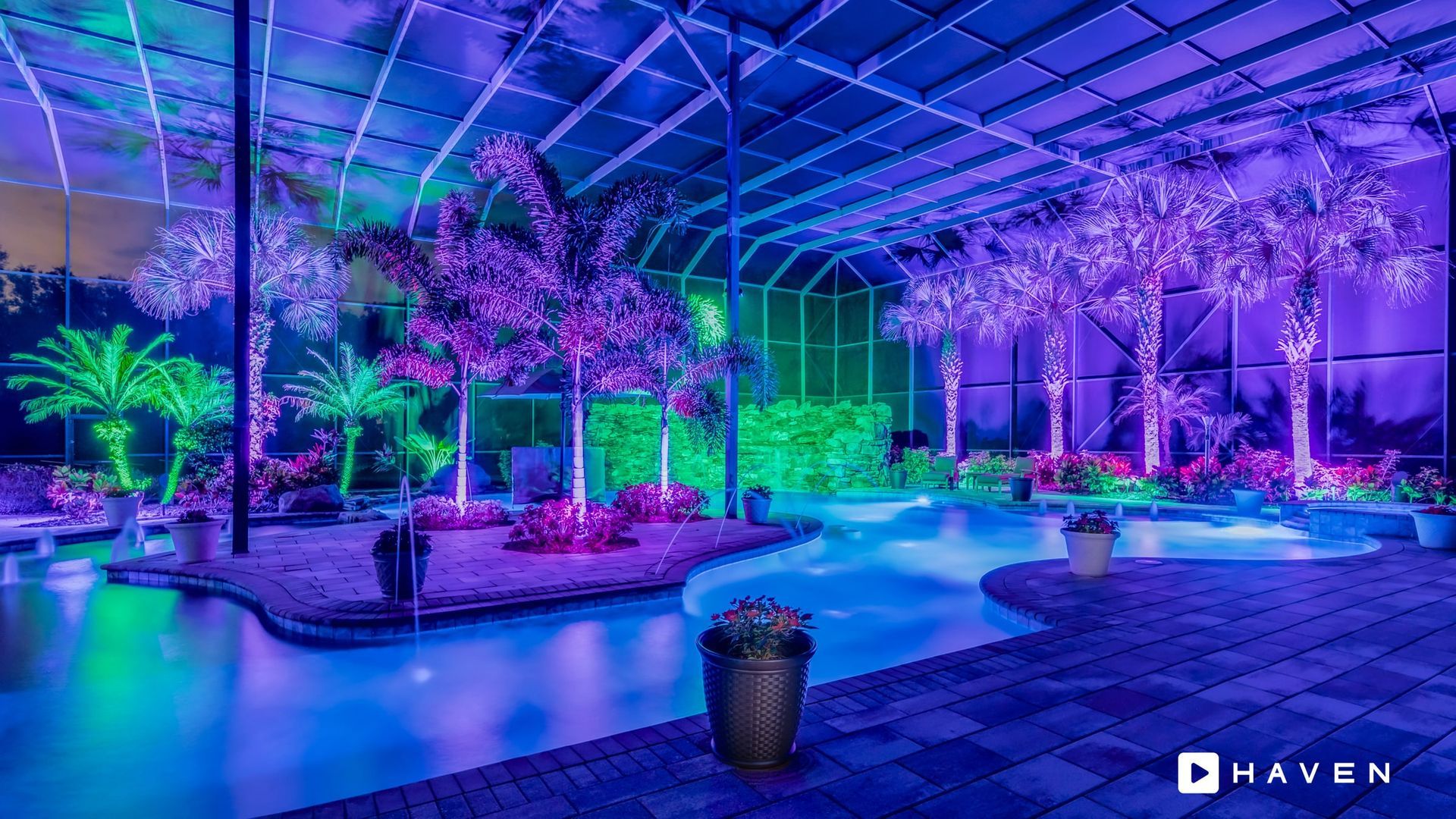 A swimming pool is lit up with purple and green lights.