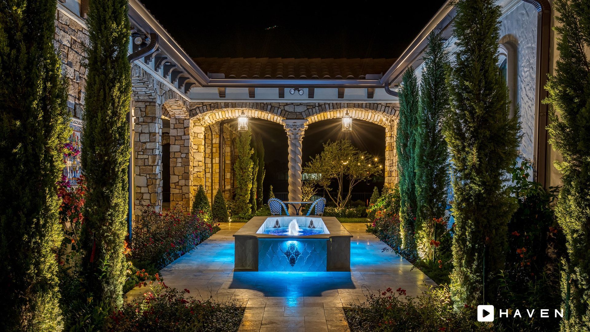 There is a fountain in the middle of the courtyard at night.