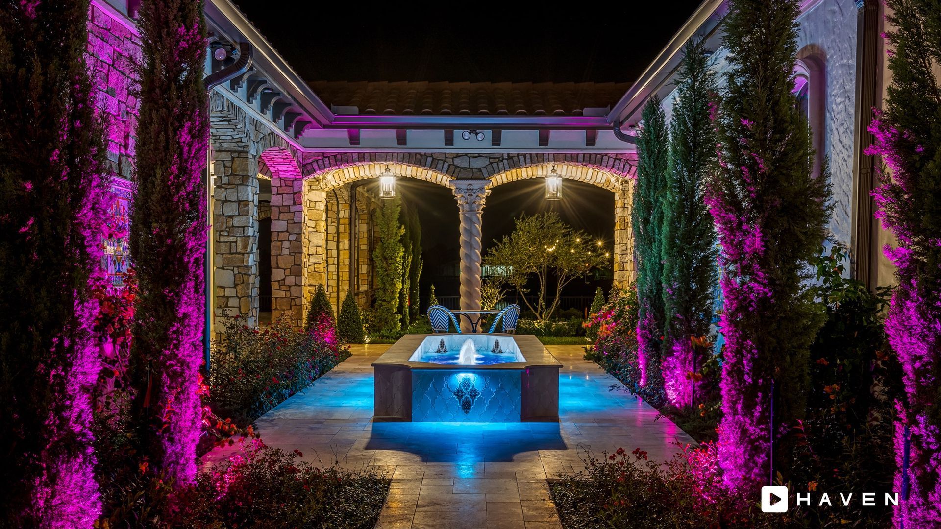 There is a fountain in the middle of the courtyard with purple lights.