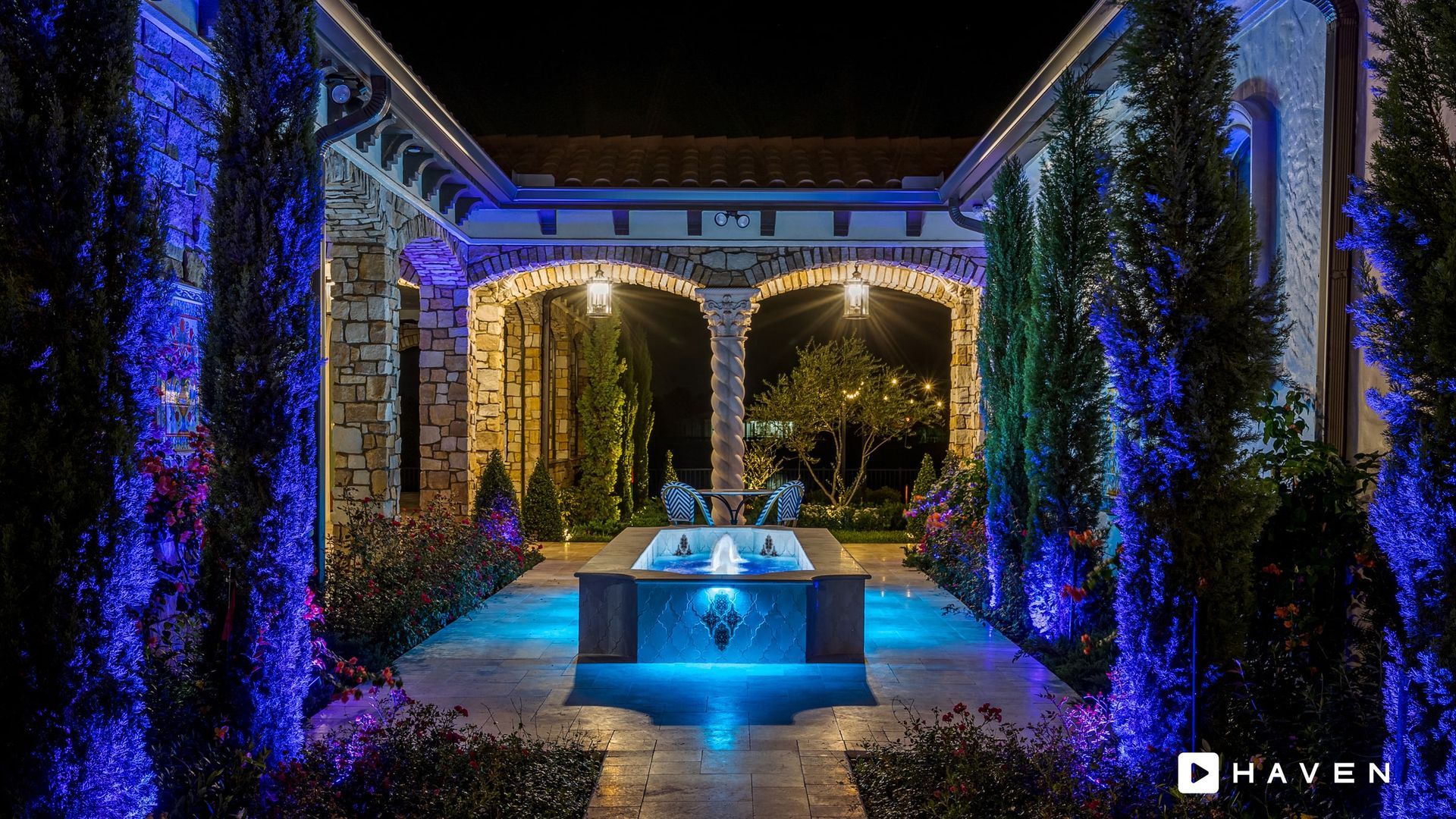 A large swimming pool is lit up at night with blue lights.