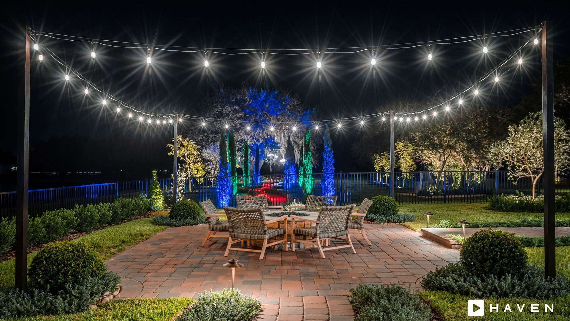 A patio with a table and chairs under string lights at night.