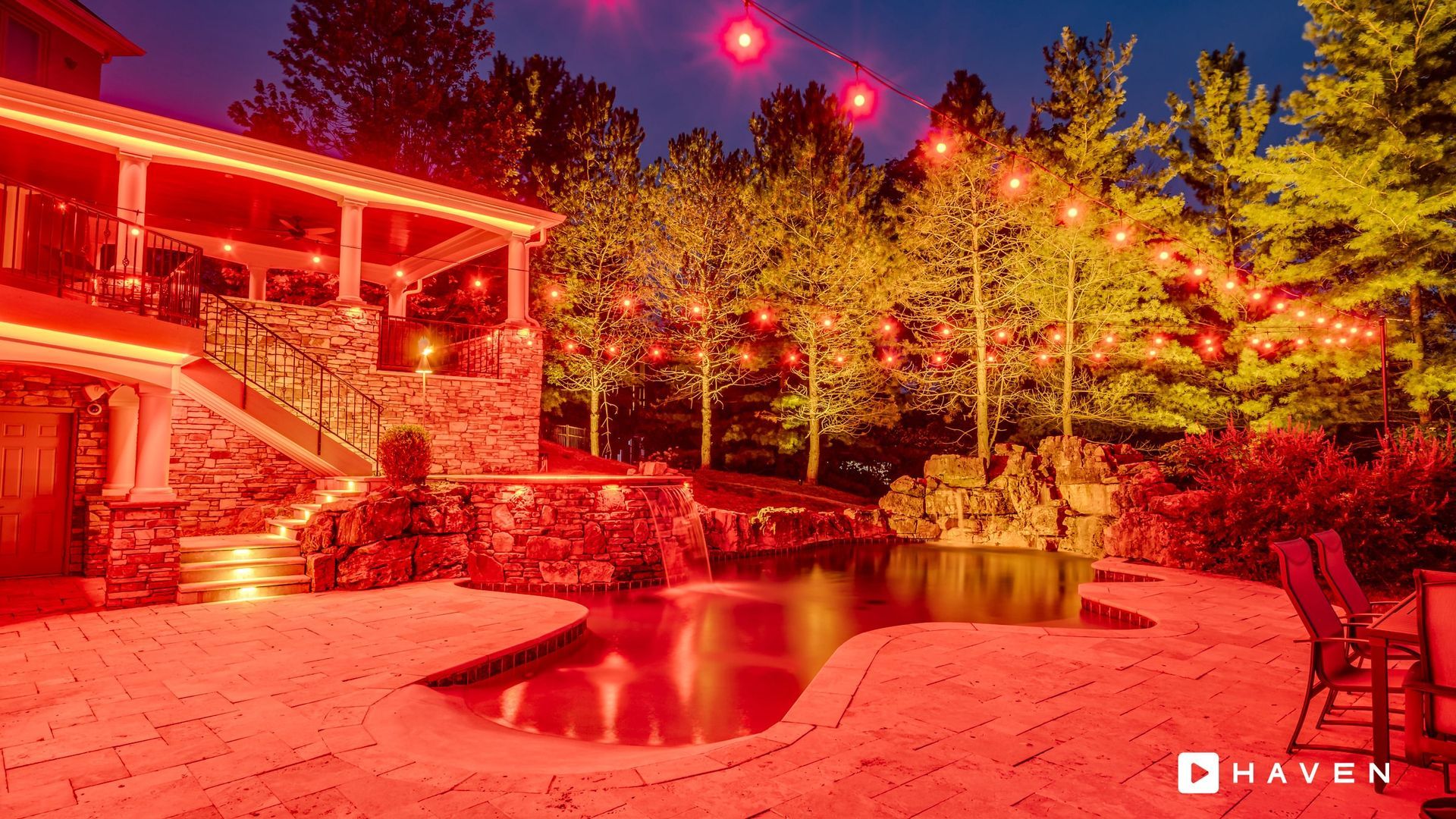 A large house with a pool in front of it is lit up with red lights.