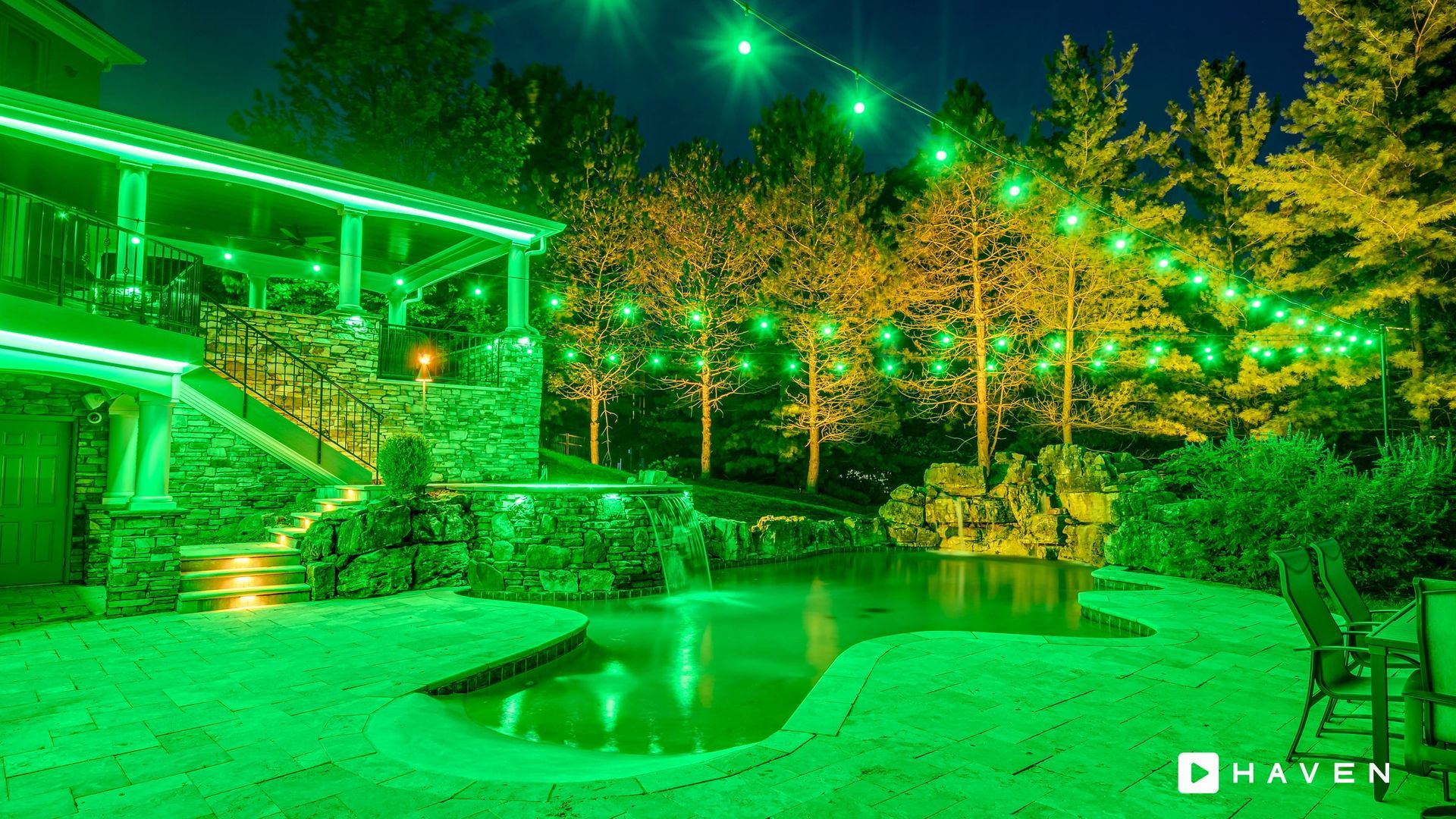 A swimming pool is lit up with green lights at night.