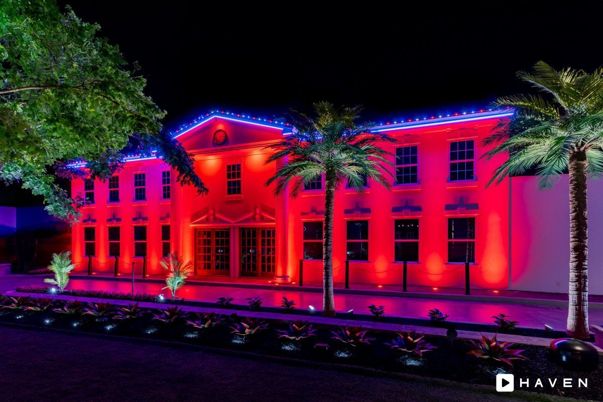 A large building is lit up with red and blue lights at night.