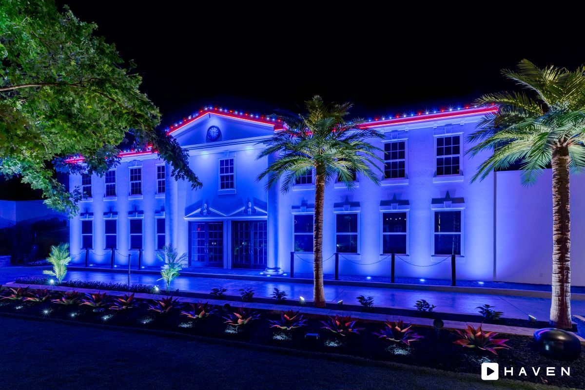 A large white building is lit up with blue and red lights.