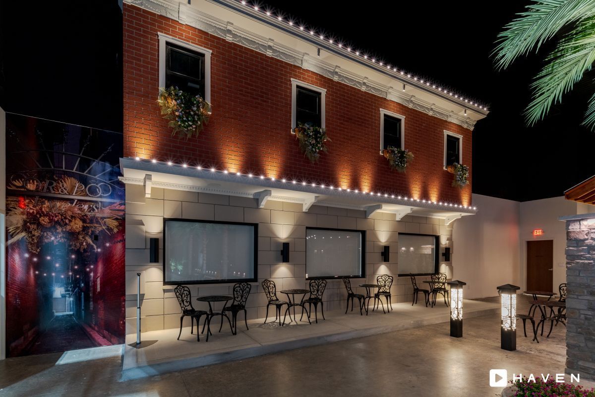 A building with tables and chairs in front of it at night.