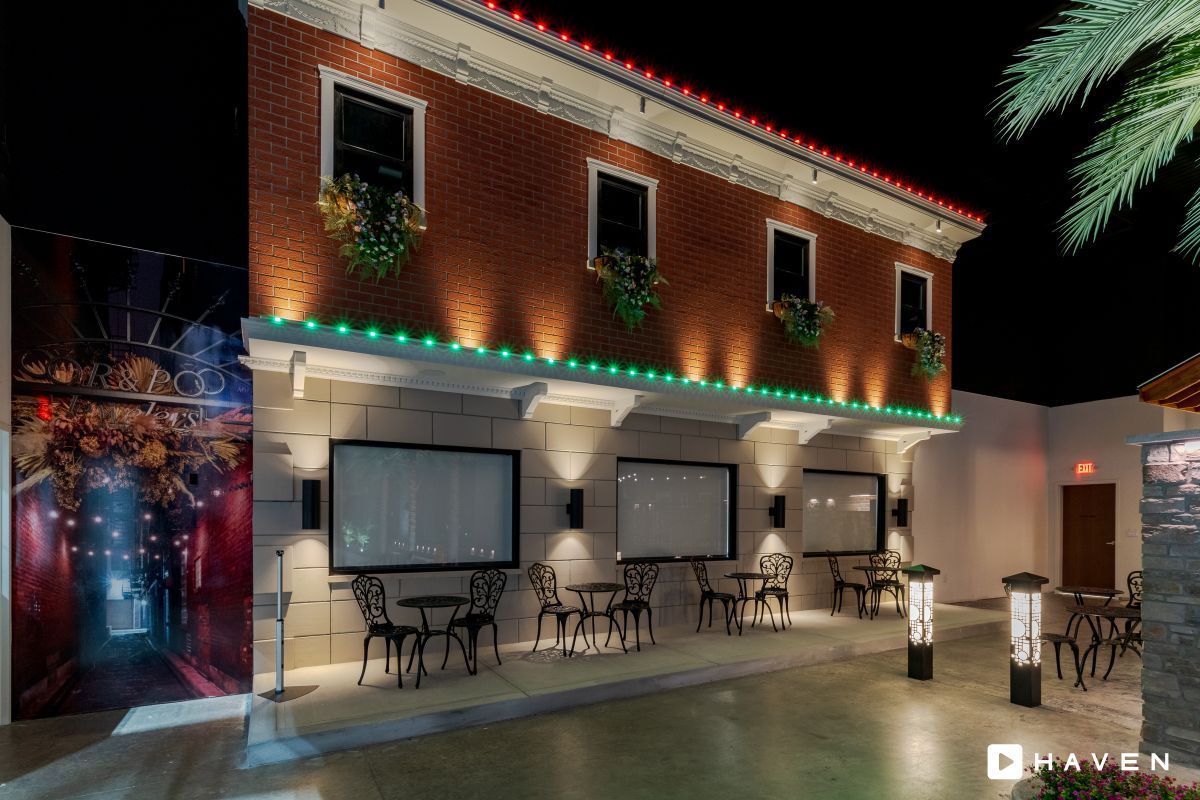 A building with tables and chairs in front of it at night