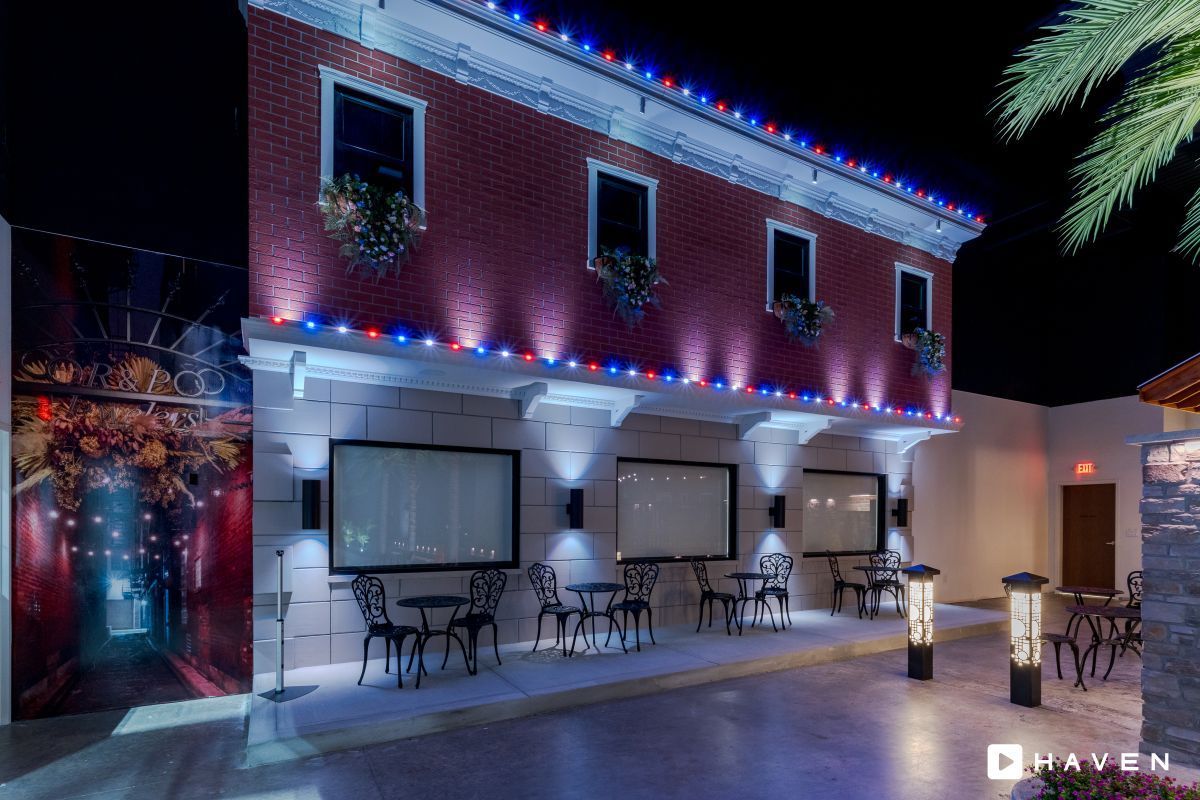 A red building with tables and chairs in front of it at night.