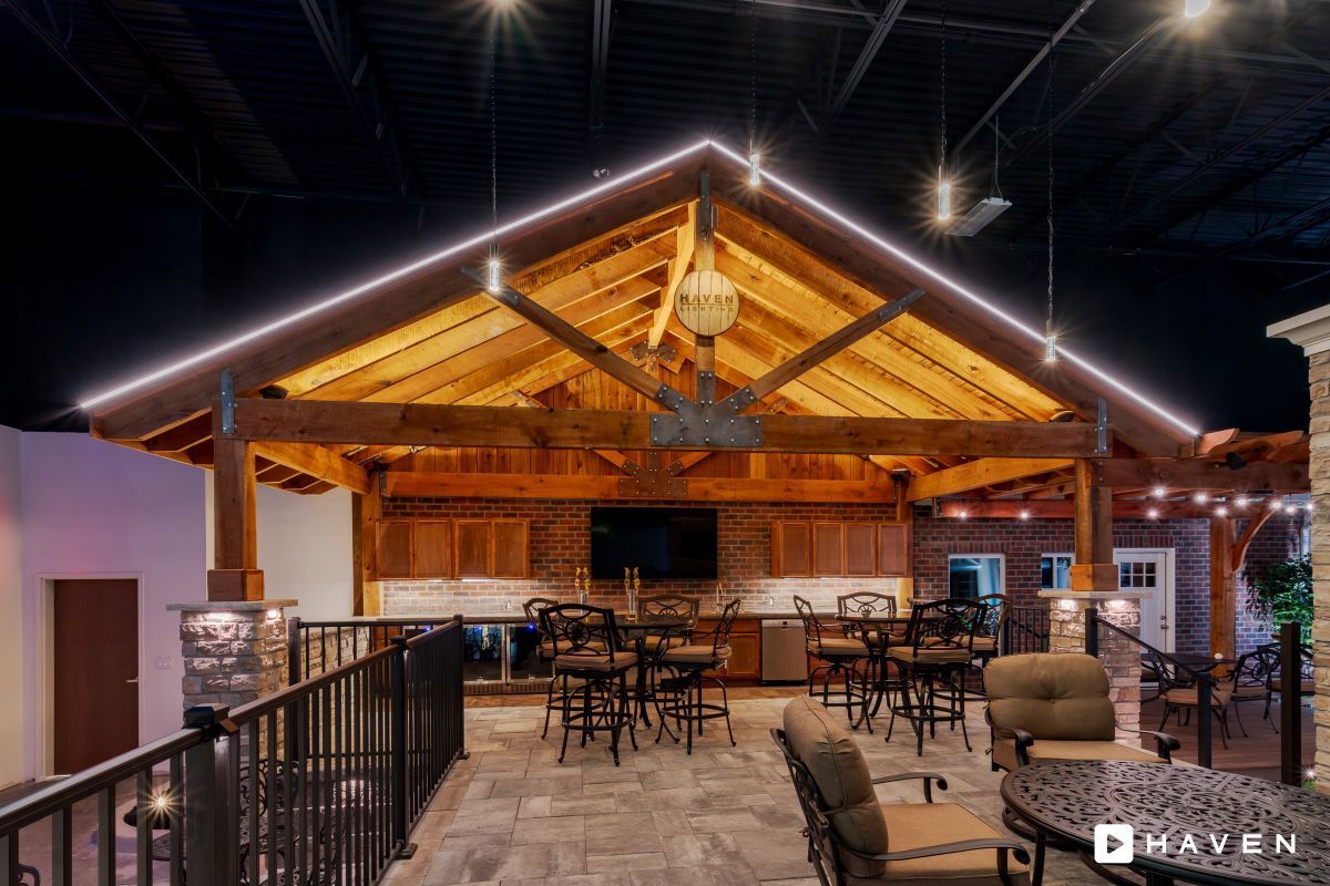 A large room with tables and chairs under a wooden roof.