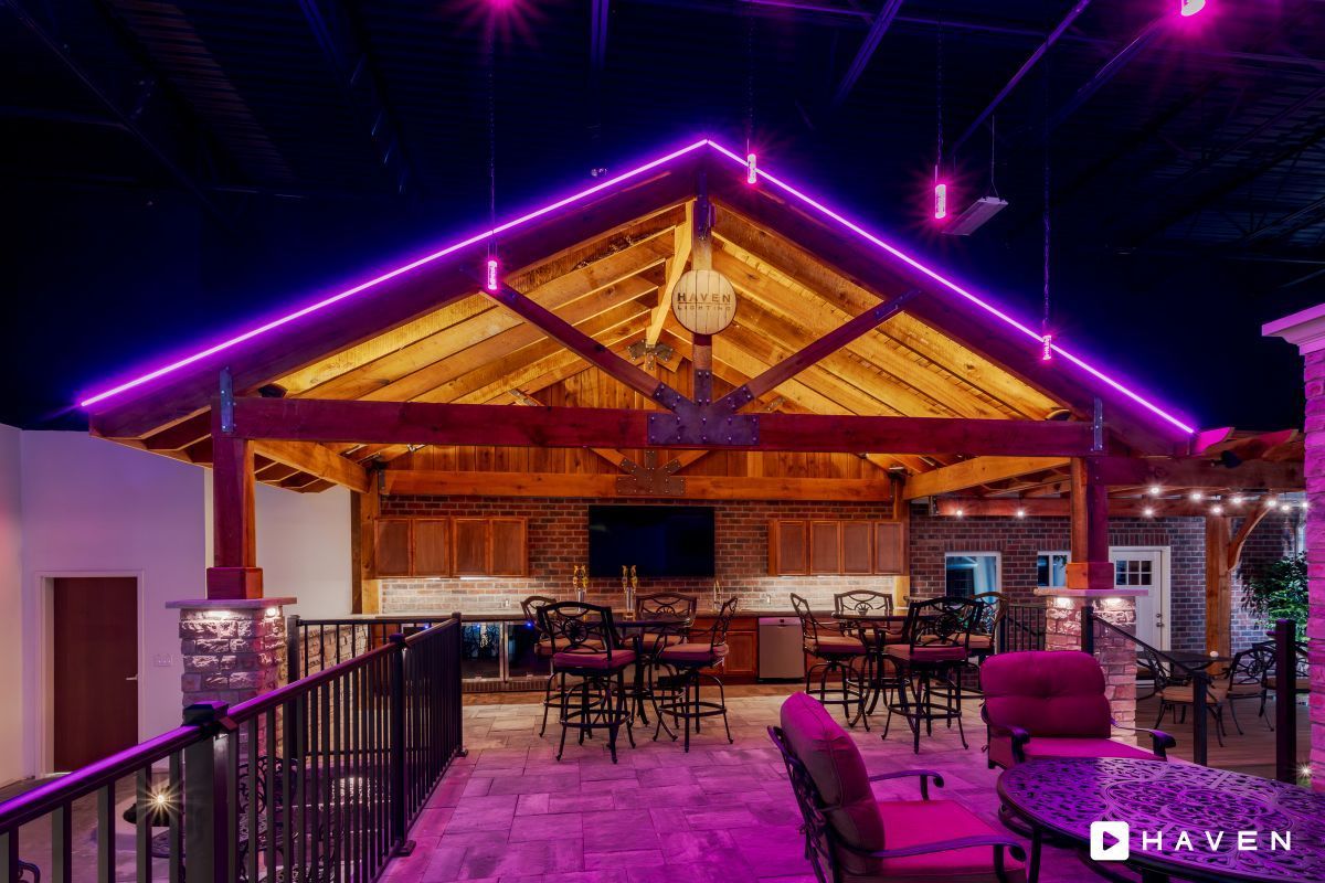 A large room with purple lights on the ceiling and tables and chairs.