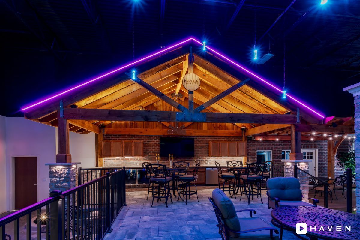 A large room with purple lights on the ceiling and tables and chairs.