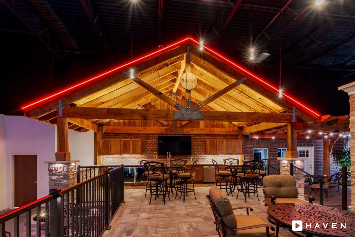 A large room with tables and chairs under a wooden roof.