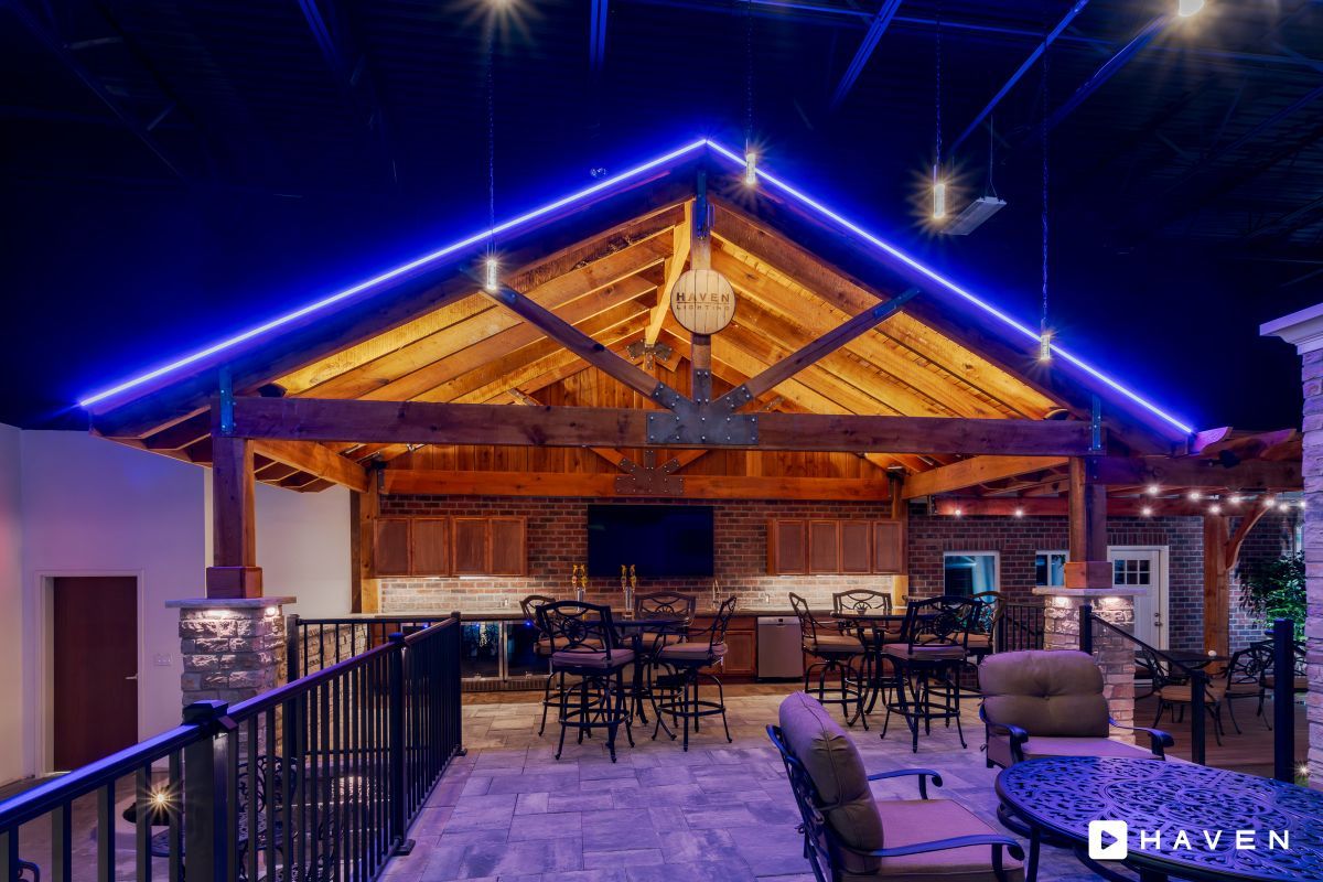 A large room with tables and chairs under a roof with blue lights.