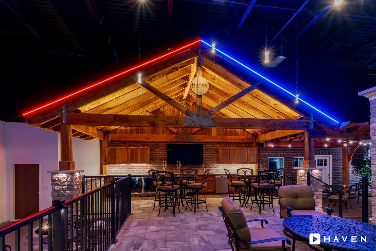 A large room with tables and chairs under a roof with red and blue lights.