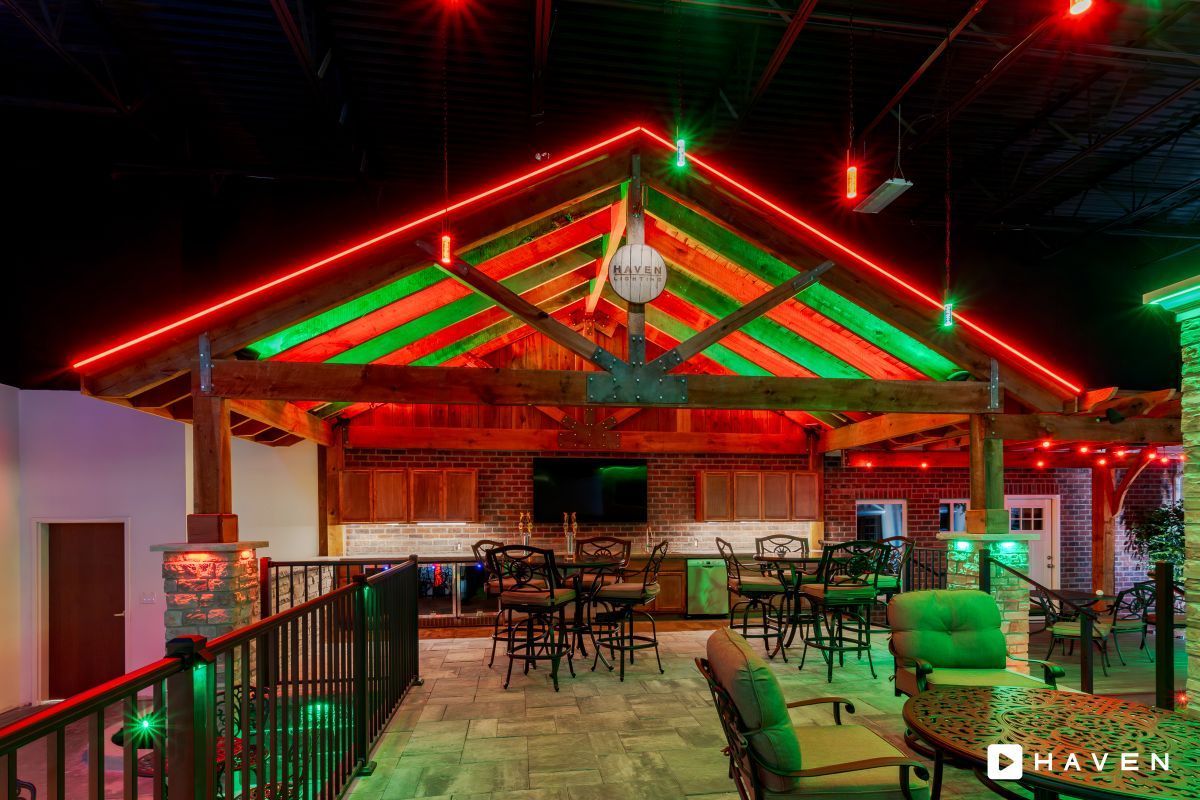 A large room with tables and chairs under a roof with red and green lights.