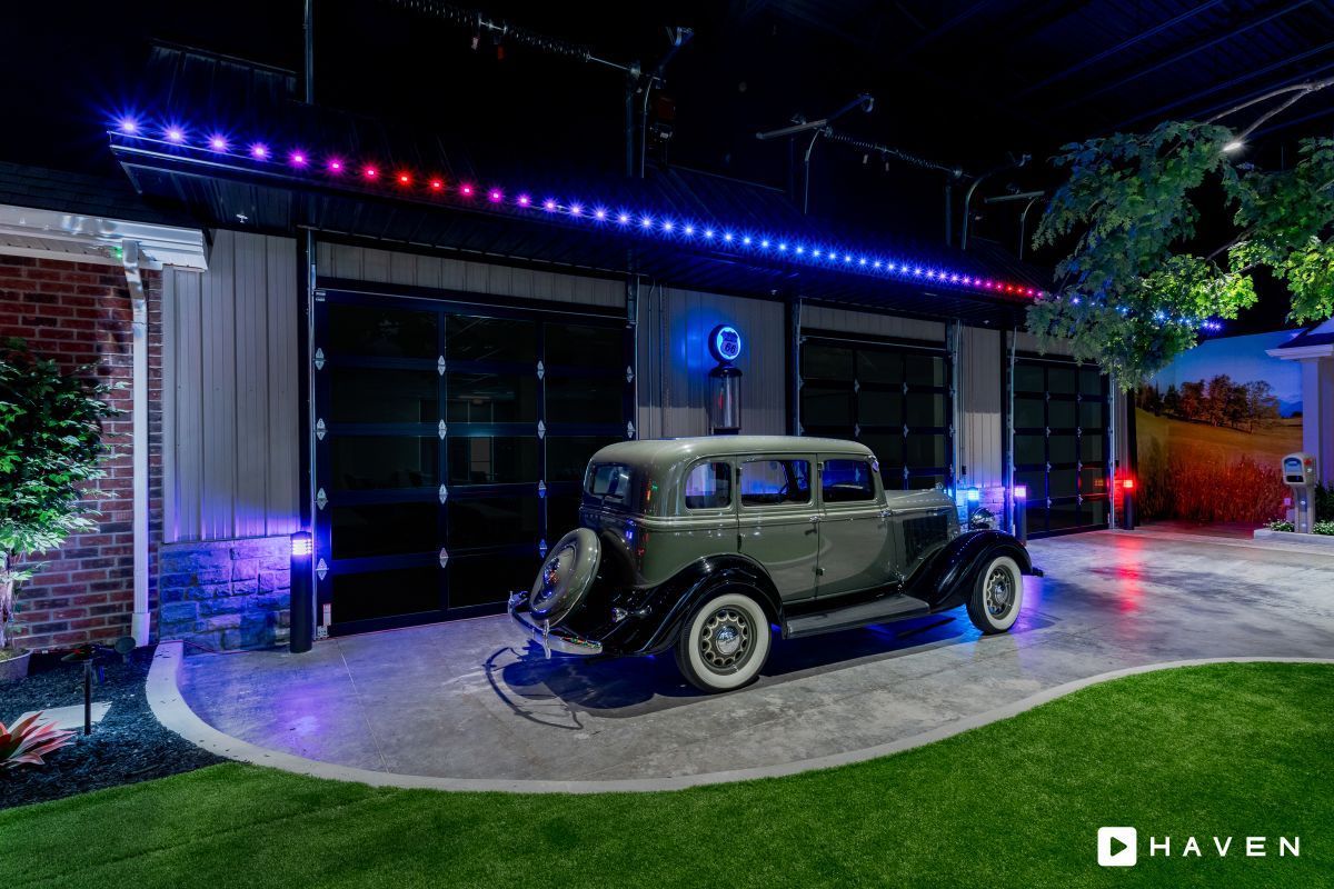 An old car is parked in a driveway in front of a house.
