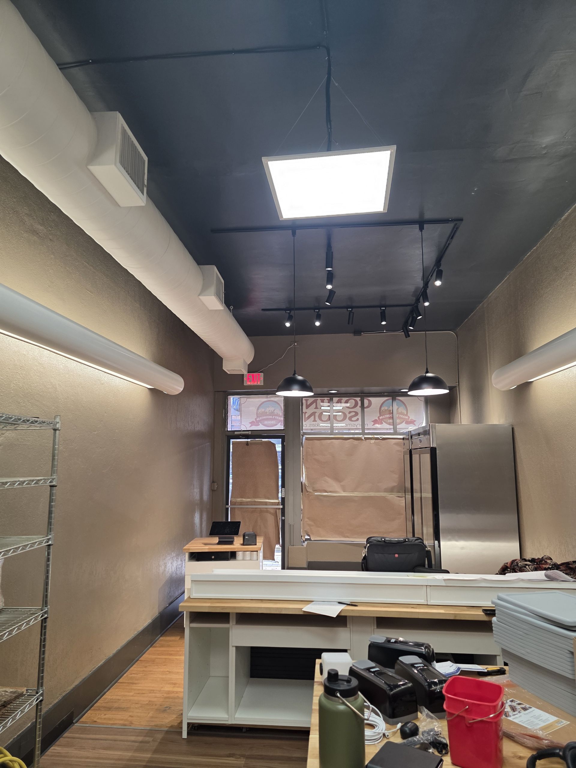 Interior of a commercial space; unfinished construction; grey ceiling, stainless steel appliances.