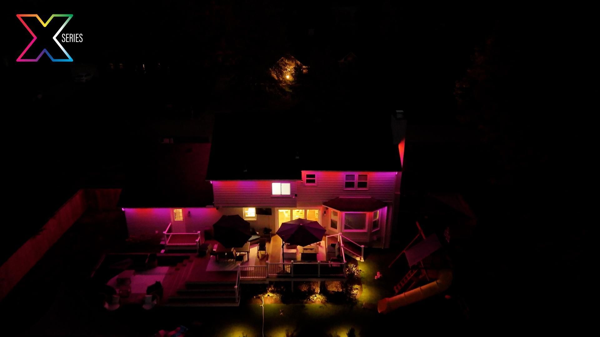 An aerial view of a house with purple lights on it at night.