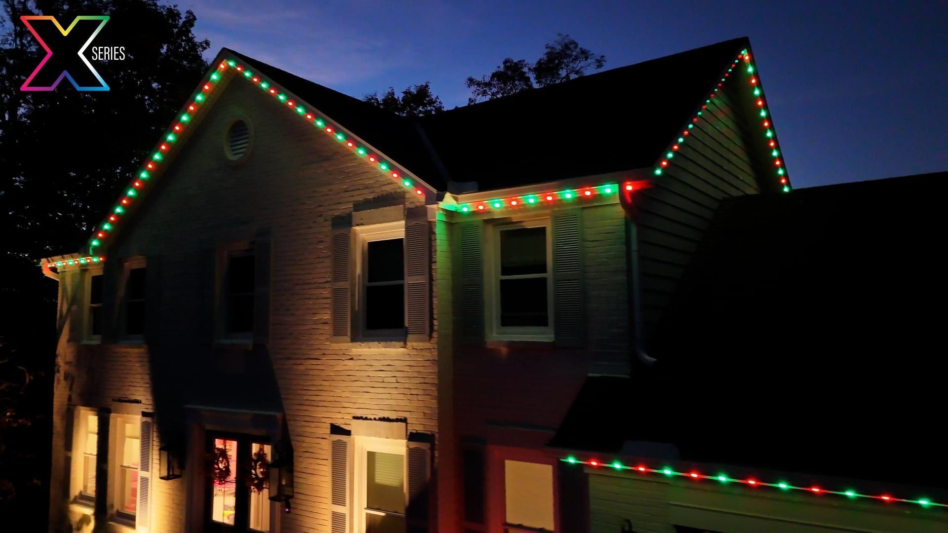 A house with christmas lights on it is lit up at night.