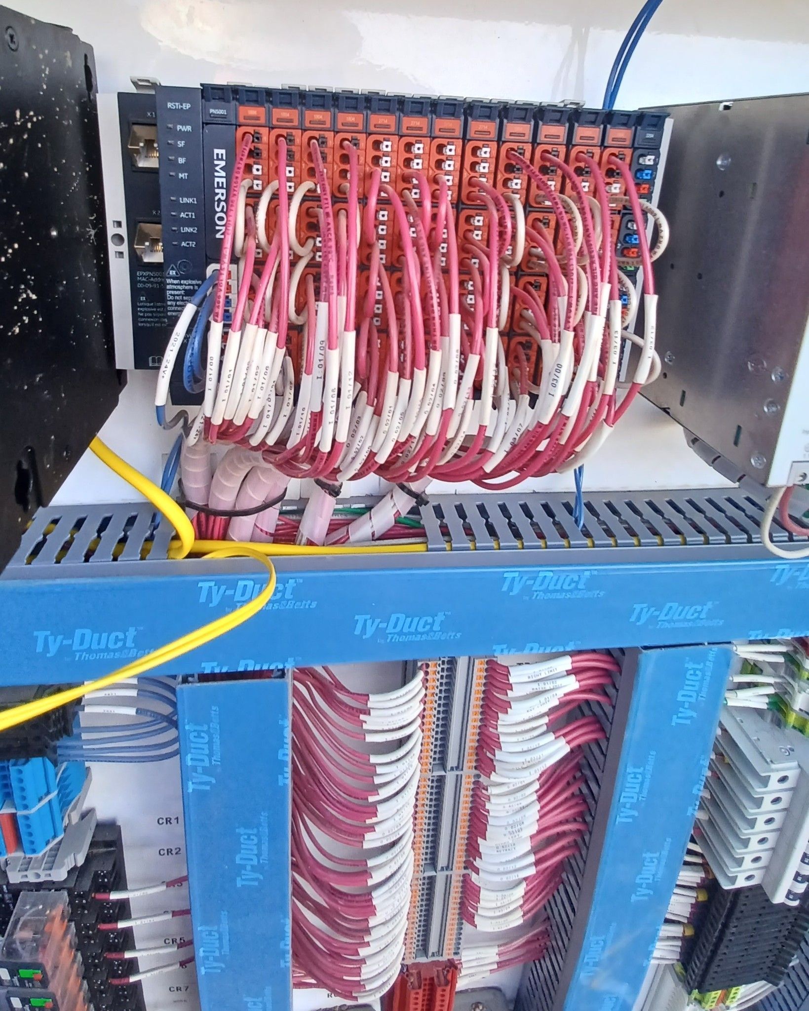 Control panel with red and white wires connected to electronic modules. Blue support beams with labels.